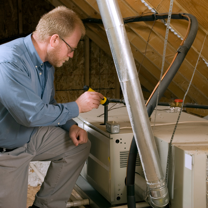 Man inspecting an air conditioner in an attic