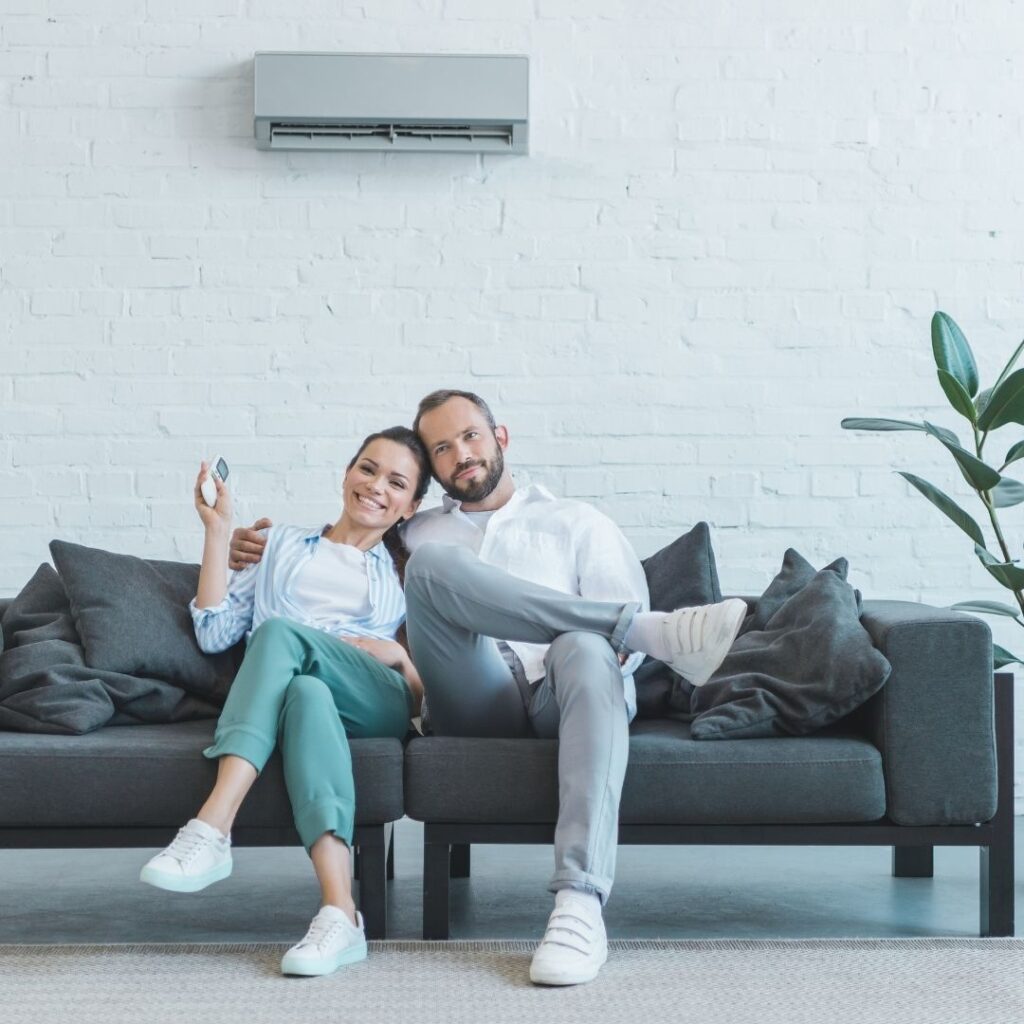 Two people in front of a new air conditioner.